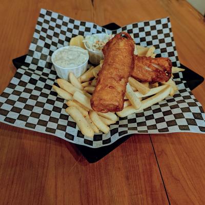 Fish and chips served with sides of coleslaw, tartar sauce and a lemon wedge.