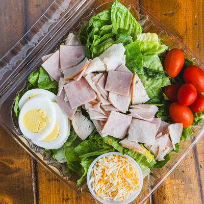 Chef Salad with lettuce, shredded cheese, eggs, tomatoes, diced ham, and diced turkey.