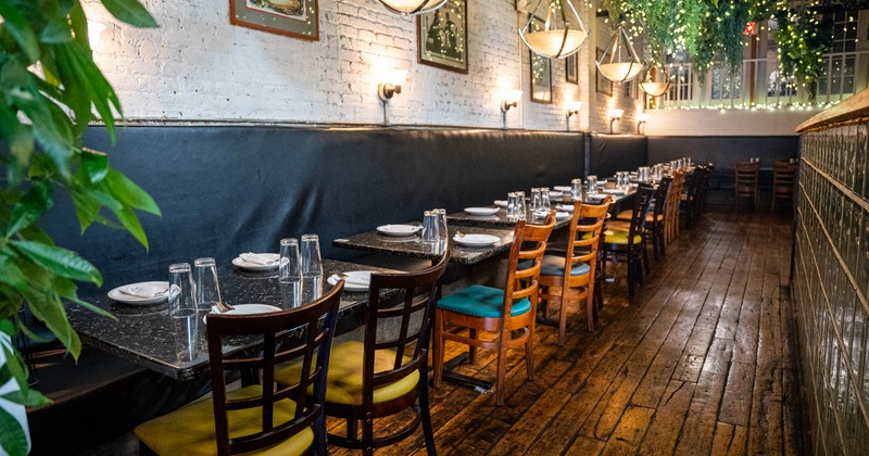 Interior, long tables, mixed chairs, white brick walls, pendant lights, and hanging plants