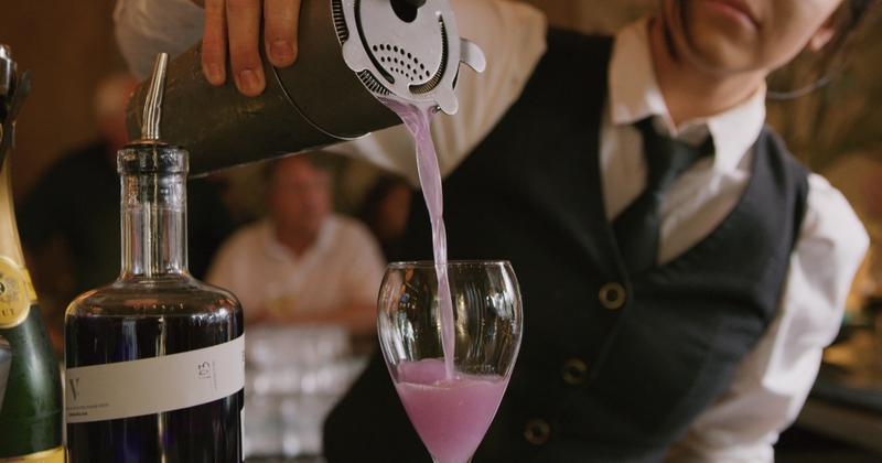 Pouring a purple cocktail into a glass