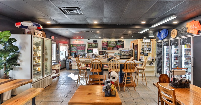 Casual dining area with a long table, regular-sized tables, and glass-front refrigerators