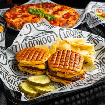Cheeseburger sliders served with sides of potato chips and pickle slices.