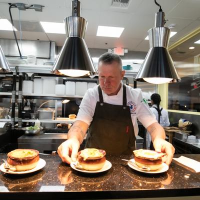 A cook places onion soup bowls on a kitchen counter.