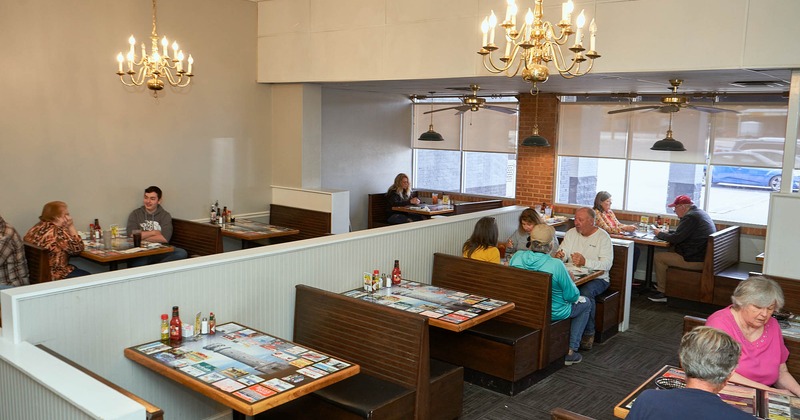 Interior, customers, chandeliers, restaurant attendant collecting plates, tables, benches, chairs