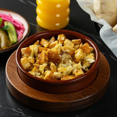 Potatoes and eggs served in a clay dish with orange juice.