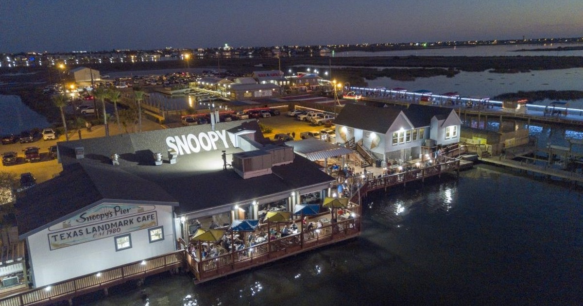 An aerial view of a restaurant at night, with twinkling lights illuminating the outdoor seating area