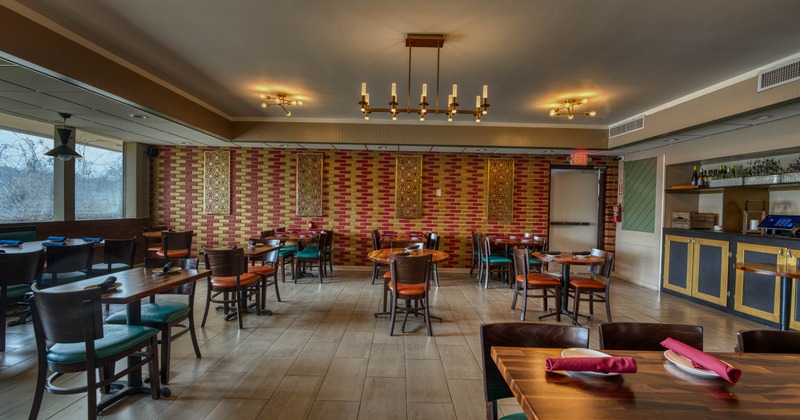 Restaurant interior with wooden tables, brick patterned wall, and large windows