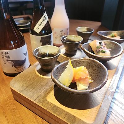Wooden tray with sake bottles, small cups of sake, and sashimi appetizers.