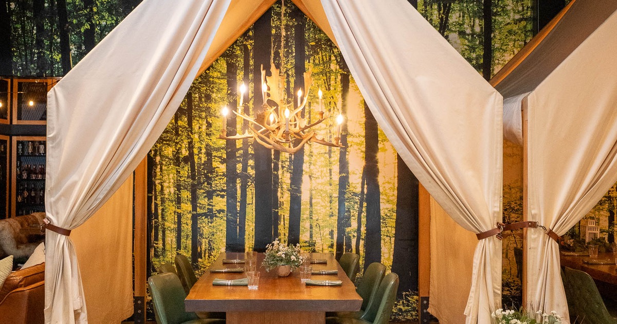 A cozy dining setup with a wooden table and green chairs under a tent-like canopy
