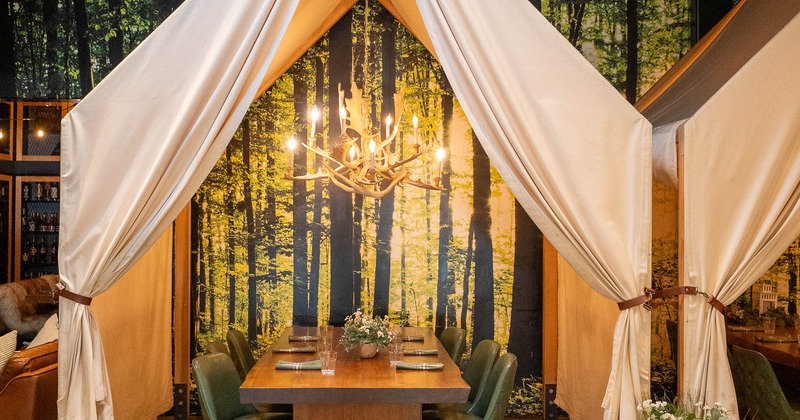 A cozy dining setup with a wooden table and green chairs under a tent-like canopy