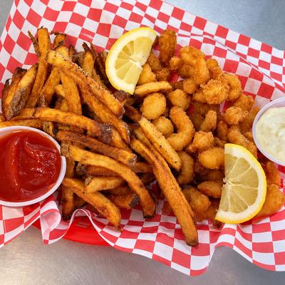 Breaded shrimp and fries in a checked basket with lemon wedges and dipping sauces..