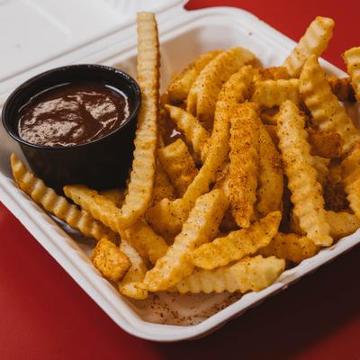 A container of crinkle-cut fries with a side of BBQ sauce.