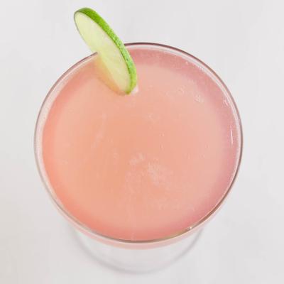 A glass of pink Cosmo cocktail, garnished with a lime wheel, top view.
