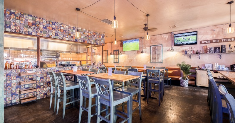 Cozy interior of a Mexican restaurant with an open kitchen area, wooden tables, and high chairs