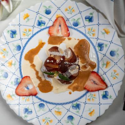 Plated poached pear with sauce on floral plate.
