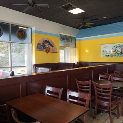 Interior of a restaurant with yellow walls, wooden tables and chairs, and large window.