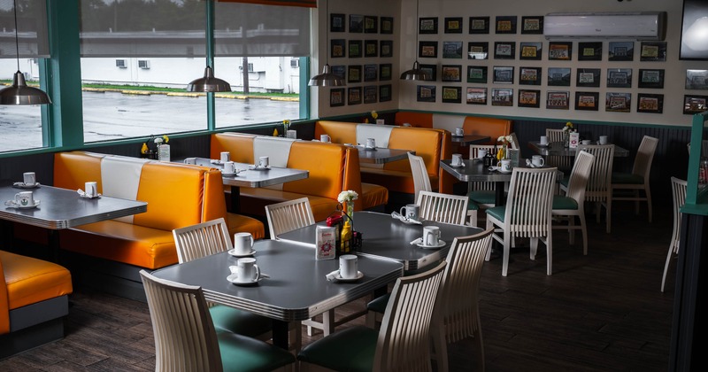 Interior of a classic American diner with orange booths and white chairs