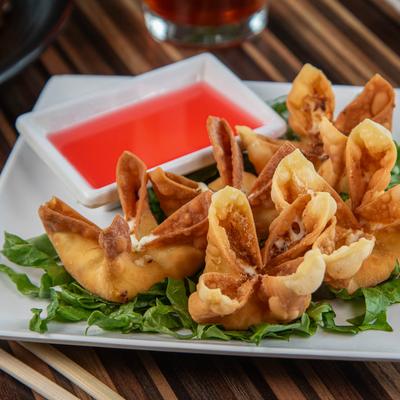 Crab Rangoon with bright red dipping sauce.