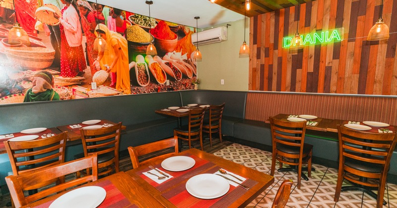 Dining area with wooden tables and chairs; colorful poster on the wall.
