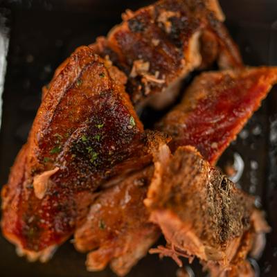 Pork ribs garnished with a sprinkle of fresh herbs, close-up.