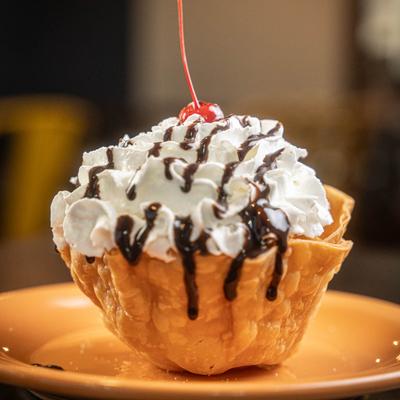 Fried Ice Cream in a tortilla bowl topped with whipped cream, chocolate sauce, and a cherry.