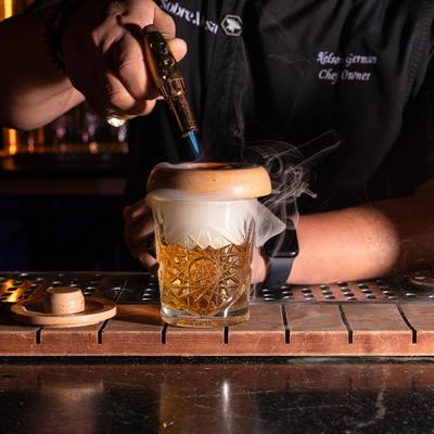 A bartender infusing a cocktail with smoke.