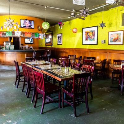 The interior featuring  wooden tiled tables, colorful decorations, and yellow walls with art.