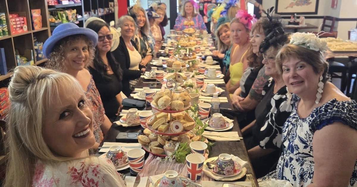 Group of people enjoying an afternoon tea party with tiered pastry stands