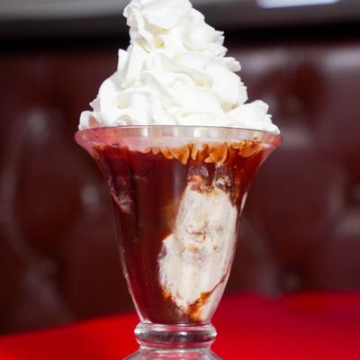 Ice cream sundae topped with a large dollop of whipped cream.