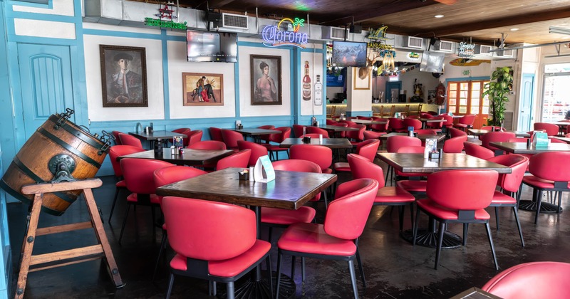 Interior, red chairs, dark wood tables, turquoise walls, neon beer signs, a bar