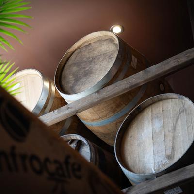 Stacked wooden barrels with metal bands are arranged on a rustic wooden rack.