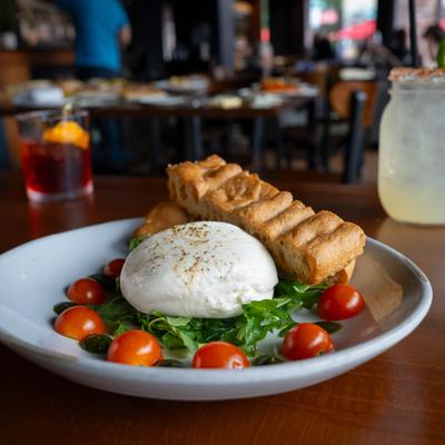 Burrata served on a bed of arugula with cherry tomatoes and house made bread.