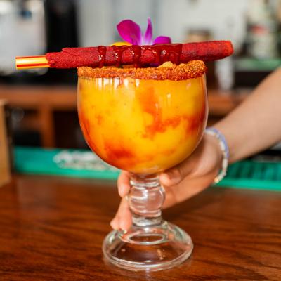 Mangonada Margarita garnished with chili rim and tamarind candy straw.