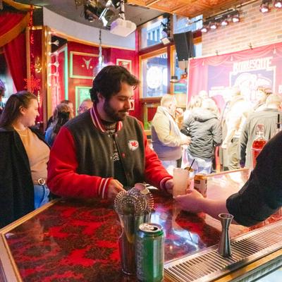 A bartender serves guest a cocktail.