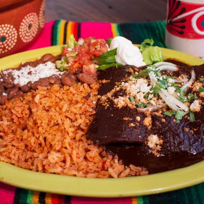 Enchiladas in Mole sauce, with rice, beans, salsa, guacamole, and sour cream.