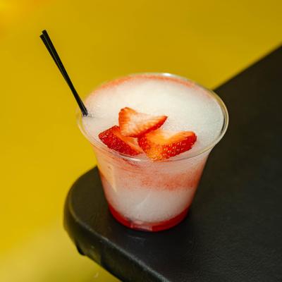 A cocktail drink garnished with sliced strawberries.