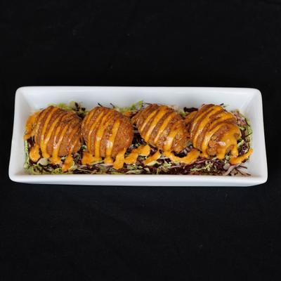 Bayou boudin balls drizzled with orange sauce served over shredded greens.