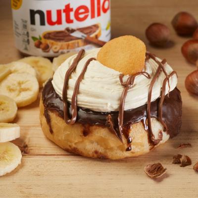 Nutella and banana donut with whipped topping and chocolate drizzle.