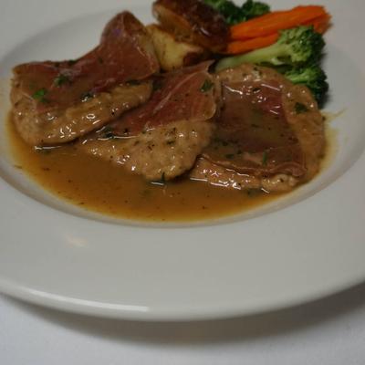 Meat medallions with vegetables in light brown sauce.