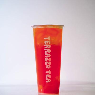 A vibrant orange and red gradient iced tea in a tall, clear Terrazzo Tea cup.