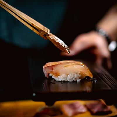Hands preparing Otoro sushi.