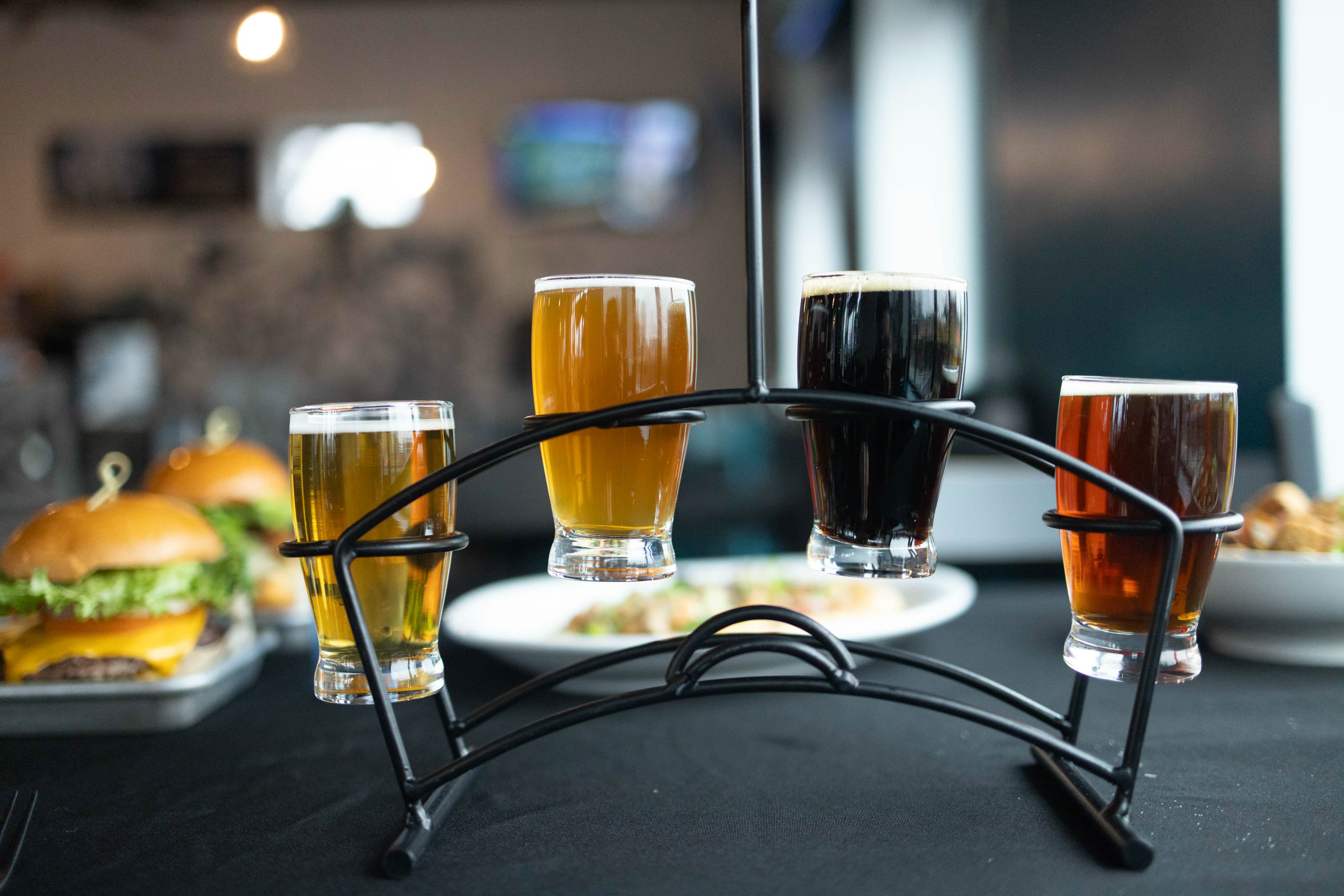 A beer flight served on a dark table with food