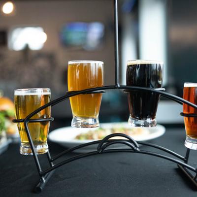 A beer flight served on a dark table with food.