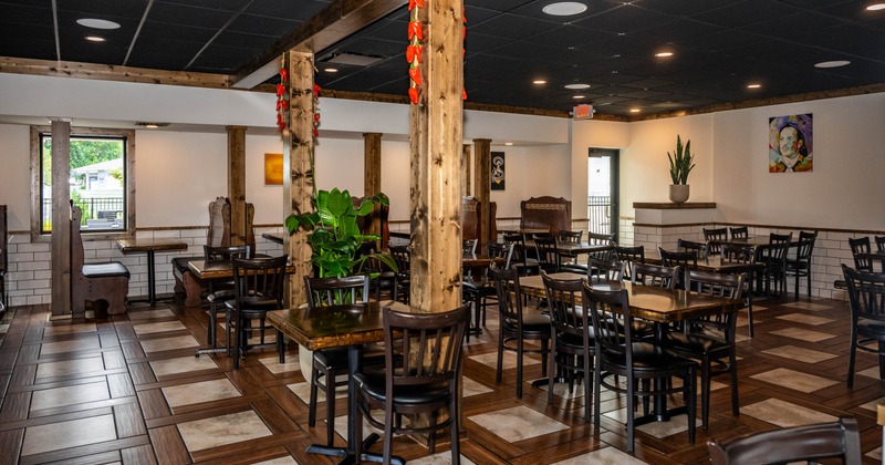 Interior of a modern restaurant with wooden tables and chairs, decorative support beams