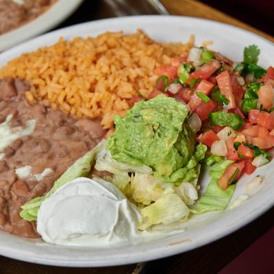 Plate of sides with rice, beans, rico de gallo, guacamole and sour creme.