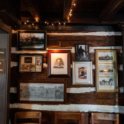 Interior featuring rustic log cabin walls and framed historic pictures.