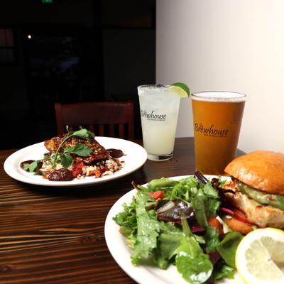 plate of Grilled salmon and plate of Grilled Chicken sandwich with house salad , Beer and margarita.