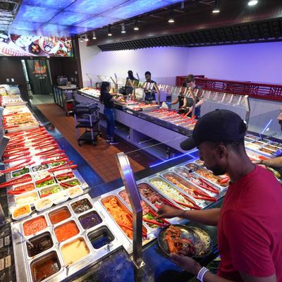 A person picking out food from serving containers.