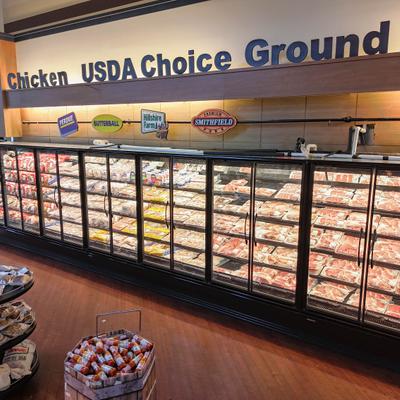 Large freezer section with packaged meat and signage.