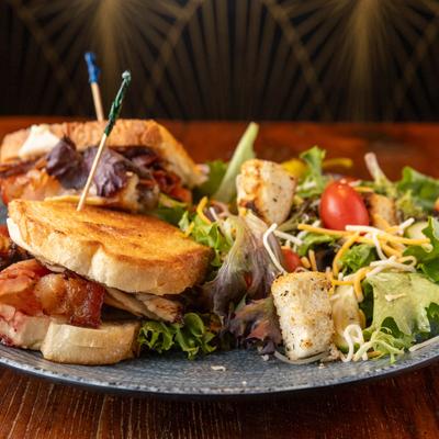 Turkey club sandwich with a side of Caesar salad on a plate.